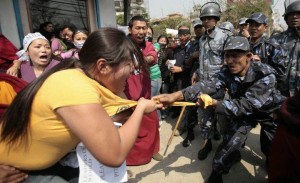 A Nepalese police tearing off a Tibetan protestor's T-shirt Photo: revolution-news.com
